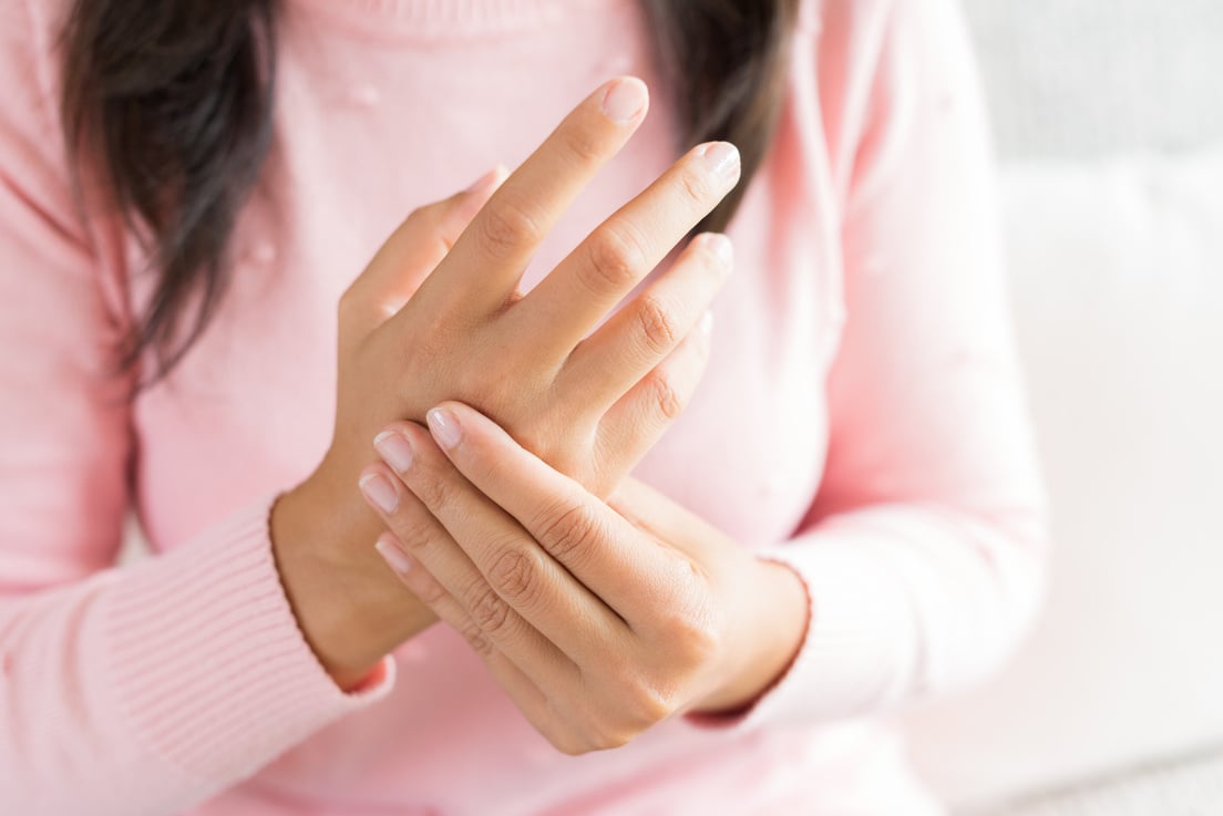 Closeup woman sitting on sofa holds her wrist hand injury, feeling pain. Health care and medical concept.