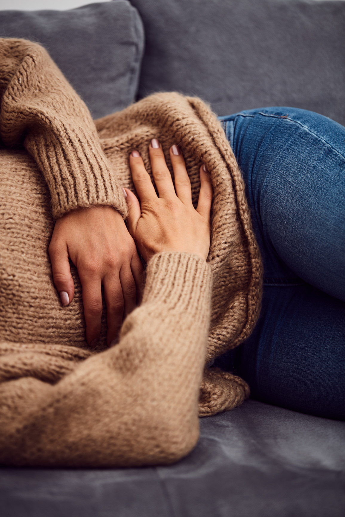 Woman having stomach issues / problems while lying on the couch.